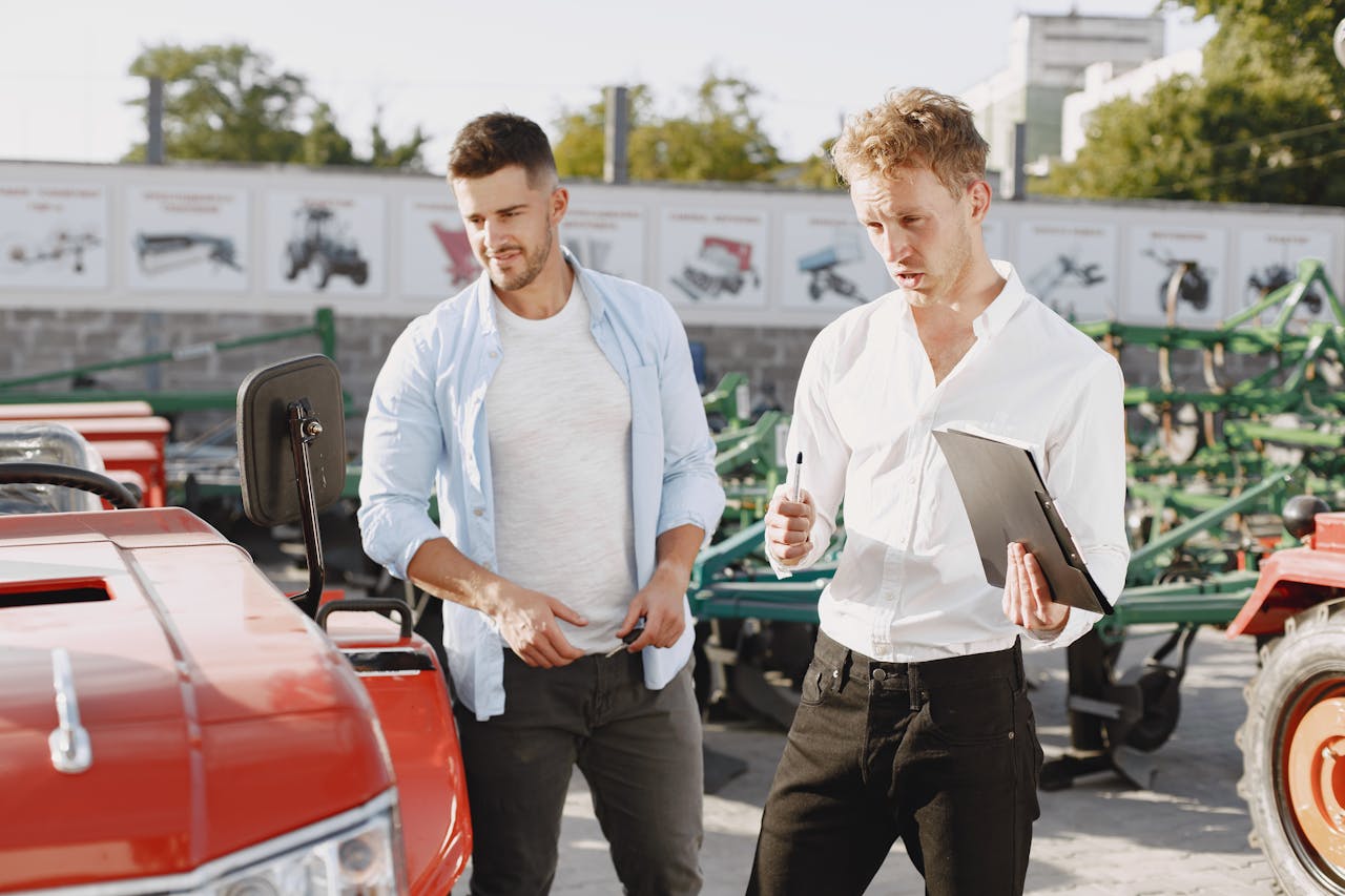Two men engaging in a discussion about a tractor sale at an outdoor dealership.